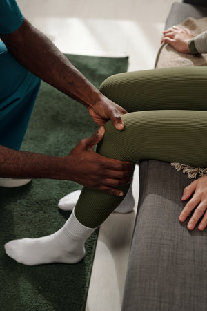 Therapist performing therapeutic massage on patient leg for recovery following injury Wearing...