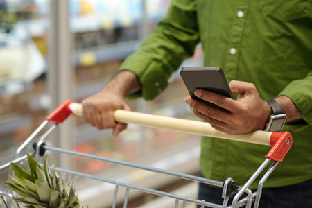 Close Up of Adult Man Using Smartphone in Supermarketの写真素材