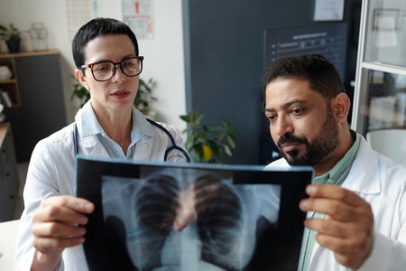 Two Doctors Looking at Chest X Ray Images in Clinic Office Discussing Patient Diagnosisの写真素材