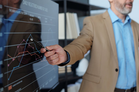 Close Up of Businessman Holding Pen Pointing at Statistical Data Graph on Board at Meeting in Office
