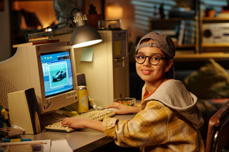 Young boy learns graphic design on vintage computer in cozy home office with bookshelves and warm...