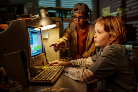 Two young boys engaging with retro computer in cozy, well-lit study room, checking data and learning together, surrounded by books and soft lightingの写真素材