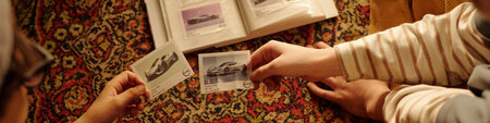 Close-up shot showing two individuals looking at photos of vintage cars on an intricately patterned...