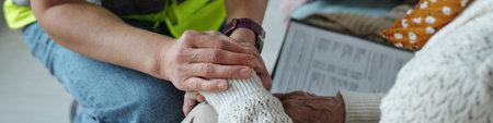 Header of female volunteer covering hand of senior refugee or homeless woman and supporting her while working with people in troubleの写真素材