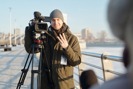 Young smiling man showing three fingers and looking at female journalist with microphone during countdown before shootingの写真素材