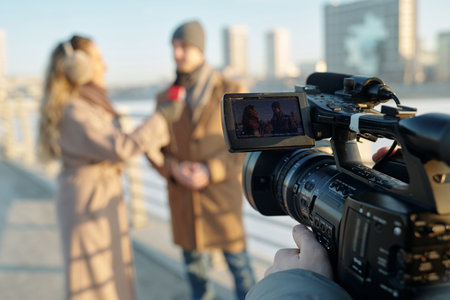 Focus on video camera with young man and woman on screen communicating during outdoor interview for...