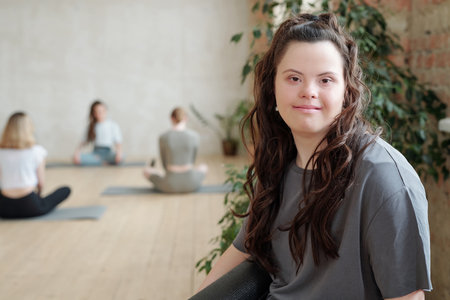 Brunette female looking at you while group of girls practicing yogaの写真素材