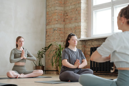 Serene females with their eyes closed keeping balance while sitting in pose of lotusの写真素材