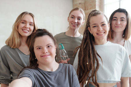 group of active girls looking at camera while making selfie in gym at breakの写真素材