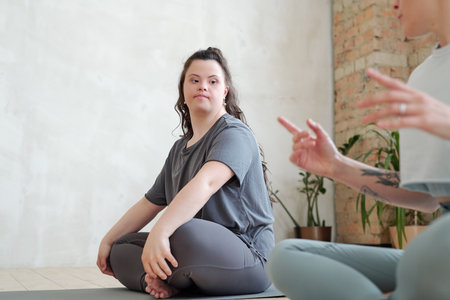 Serious female in activewear looking at yoga trainer during workout and listening to herの写真素材