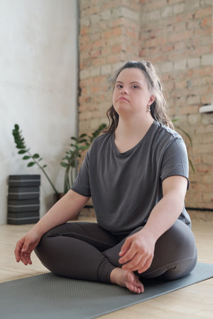 Young woman in activewear looking at you while sitting on mat during trainingの写真素材