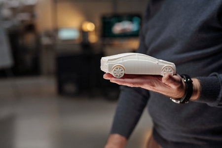 Cropped shot of unrecognizable male designer of automobiles holding car model on hand during presentation of new projectの写真素材