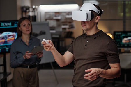 Focus on young man with VR headset making virtual presentation of new project while pressing button on remote controlの写真素材