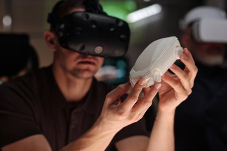 White car model in hands of young modern designer wearing VR headset studying characteristics of...