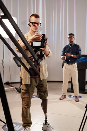 Operator with robotic leg shooting video in studio with African man on background