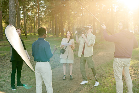 Young African man speaking in front of disabled cameraman and shooting groupの写真素材