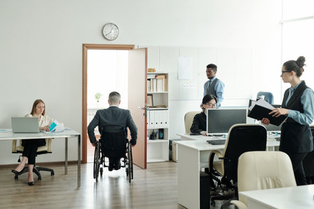 Businessman in wheelchair moving towards his office in working environmentの写真素材