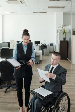 Disabled boss and his secretary discussing new contract in large office