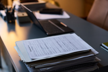 Stack of psychological paper documents standing on desk with laptop, pens and other supplies necessary for counselor workの写真素材