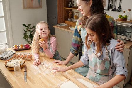 Mother and her two daughters baking together in cozy kitchen filled with natural light and warmth