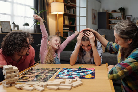 Family gathered around table, celebrating a win during competitive board game night, with expressions of joy and camaraderie evident. Homey background filled with cozy detailsの写真素材