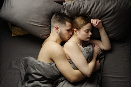 Couple sleeping closely, embracing each other under grey bedding. Captured moment showing intimacy and peace.の写真素材