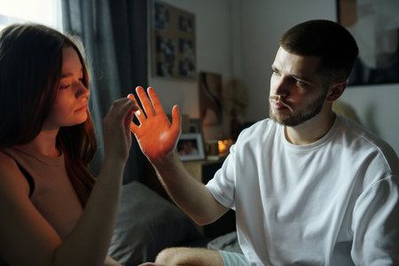 A woman and a man inspecting light reflection on her palm in a cozy, dimly lit room with various decor elements and soft shadows emphasizing their interactionの写真素材