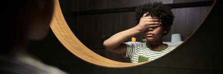 Header of boy with striped shirt standing in front of a mirror holding hand over face evoking...