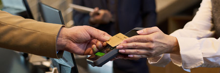 Close-up of hands exchanging credit card at checkout terminal during payment process. Handing over...