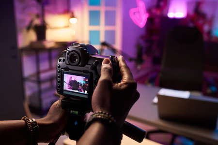Photographer holding a professional camera, capturing scene decorated with vibrant lighting and...