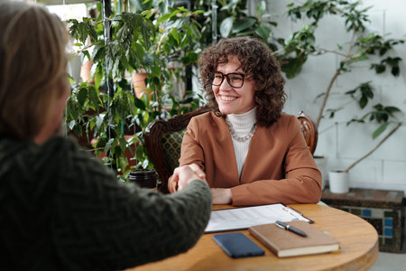 Conversing in lively cafe, two people engage in friendly discussion, sharing ideas and shaking hands...