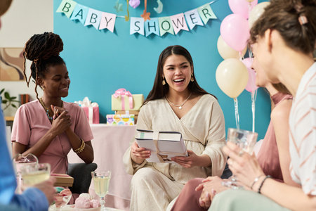 Group of young adult women including Black woman and Caucasian woman sitting together smiling and...
