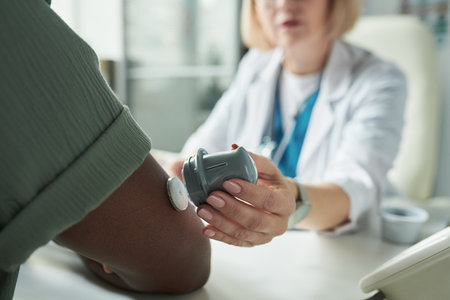 Middle aged Caucasian female doctor examining Black mans arm using glucose monitoring device during diabetes consultation in medical office, focusing on patient care and health managementの写真素材