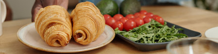 Close-up of freshly baked croissants being served on plate with fresh vegetables like cherry...