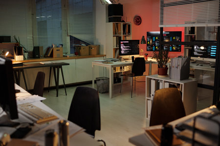 Empty office with multiple computer workstations displaying scam call center dashboards, monitors...