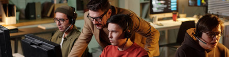 Multiethnic group wearing headsets operating computers in scam call center, Caucasian man...