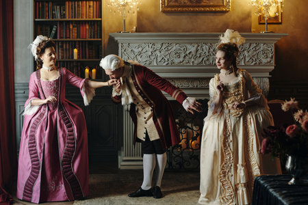 Caucasian middle aged man bowing and kissing hand of Caucasian middle aged woman in ornate Baroque costumeの写真素材