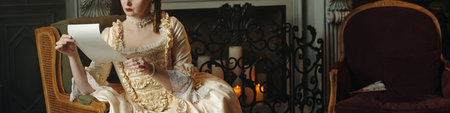 Caucasian young adult woman sitting on ornate chair reading letter in Baroque or Renaissance style...