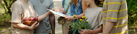 Group of multiethnic teenagers and middle aged Caucasian woman standing outdoors, teenagers holding...