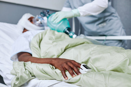Selective focus on hand shot of unrecognizable medical worker doing CPR for young injured man in hospital wardの写真素材
