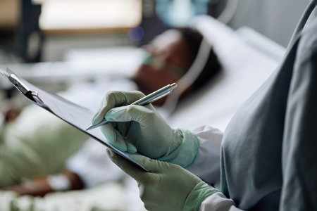 Selective focus close-up of unrecognizable doctor wearing latex gloves checking patient making notes in medical cardの写真素材