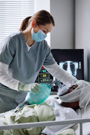 Caucasian female nurse working in hospital ward with injured Black man giving him mechanical...