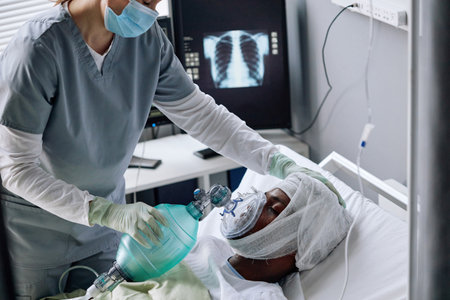 High angle view of professional medical worker helping injured young Black man to restore his breath with artificial ventilationの写真素材