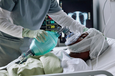 Unrecognizable nurse saving life of injured young Black man setting mechanical ventilation for him in hospital wardの写真素材