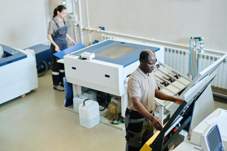 High angle view selective focus shot of African American man and Caucasian woman working in printing...