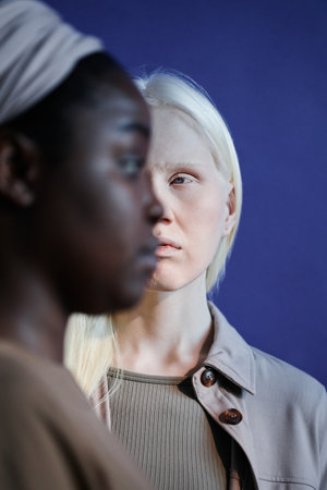 Vertical selective focus shot of young Black and Caucasian women standing with half of their faces...
