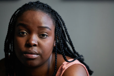 Horizontal close-up portrait shot of beautiful young Black woman with afro braids hairstyle looking...