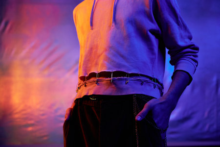 Horizontal medium section shot of unrecognizable young man wearing stylish casual outfit standing in neon lightの写真素材