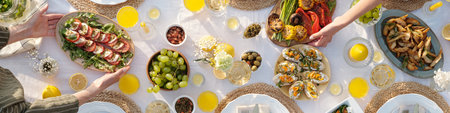 Overhead view of multiethnic adult hands serving assorted dishes including oysters, grilled...