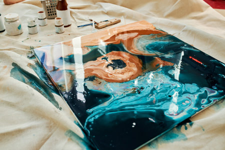 Horizontal shot of new wet abstract fluid art painting placed on piece of fabric to protect floor